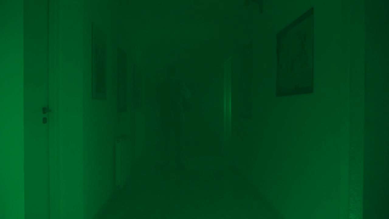 hombre con traje protector en un corredor largo y nebuloso rocía líquido desinfectante en las paredes