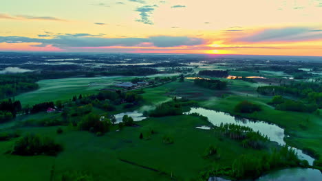 Sunset-over-verdant-landscape-with-lakes.-Aerial-backward