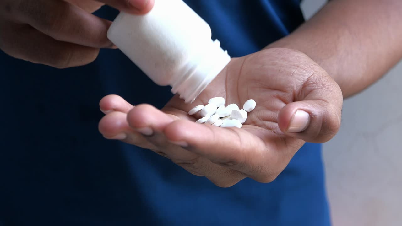 Persona che versa pillole da un flacone nella mano