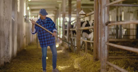 confident mature male farmer holding pitchfork in stable 11