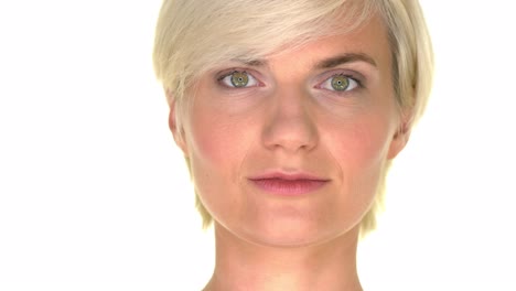 close-up of a woman's face who has green eyes and short blonde hair, slightly smirking at the camera on a seamless white studio background