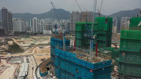 drone flight towards construction site of buildings with cranes in hong kong