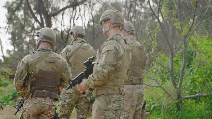 Vista posteriore di soldati militari di etnia mista che si addestrano con il fucile nei campi durante l'addestramento militare 4k