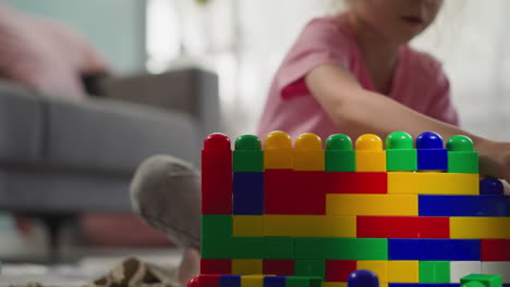 chica linda toma bloques de plástico de colores para construir la estructura