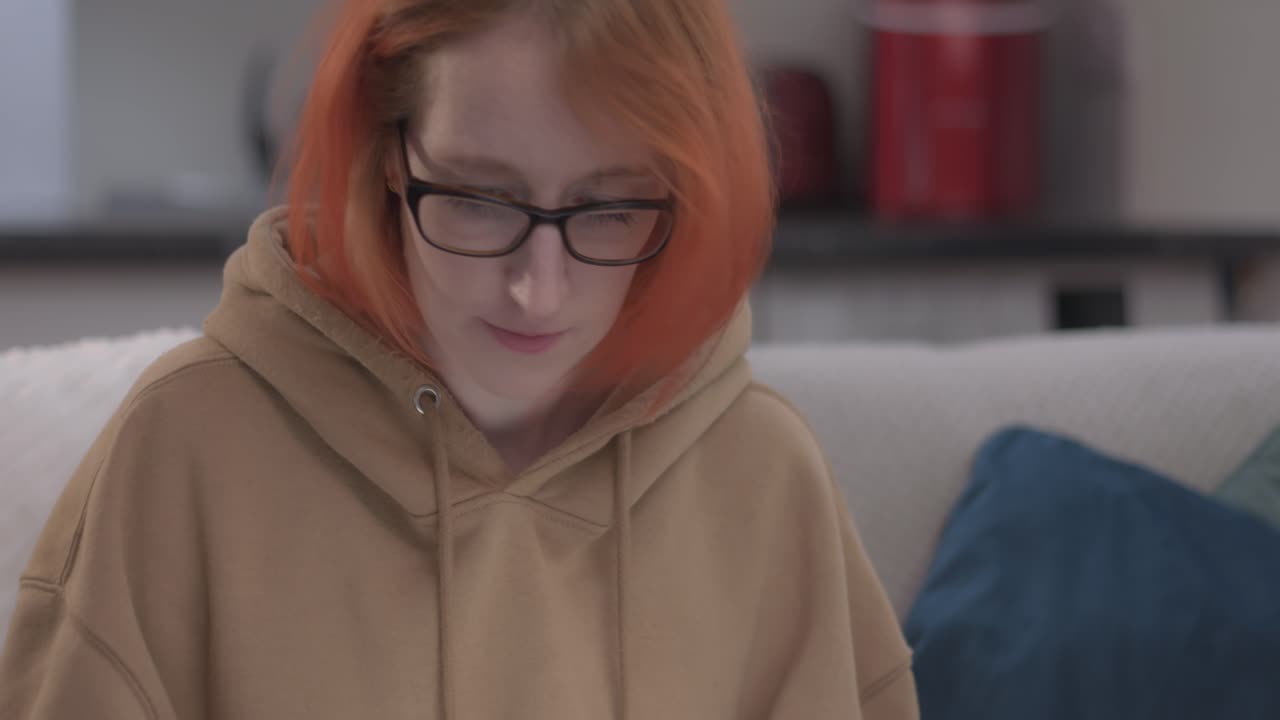 노트북으로 작업하는 원격 여성이 집에서 소파에 앉아 있습니다.