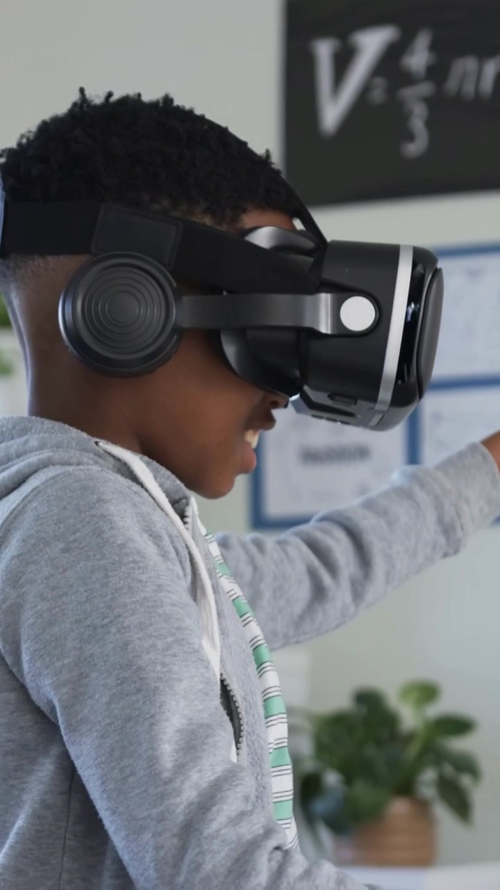 Vertikal video: VR-headset starter, studerende i grå hættetrøje og stribet T-shirt tager en genstand i klassen