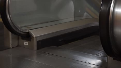 ángulo bajo del hombre caminando por la escalera mecánica, sólo la parte inferior del cuerpo