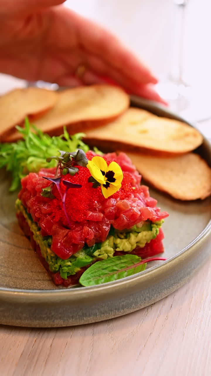 Tuna tartare with avocado and toast. Layered tuna tartare with avocado served with toast and greens