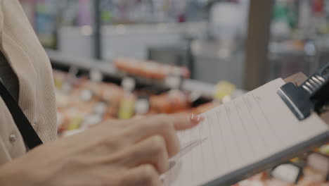 woman checking a shopping list in a grocery store