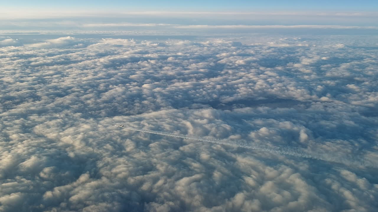 vista increíble desde la cabina de un avión que vuela alto por encima de las nubes dejando un largo rastro de aire de vapor de condensación blanco en el cielo azul