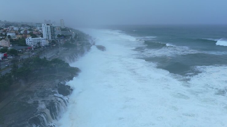 Aerial flyover foamy coastline of city in Dominican Republic during foggy day