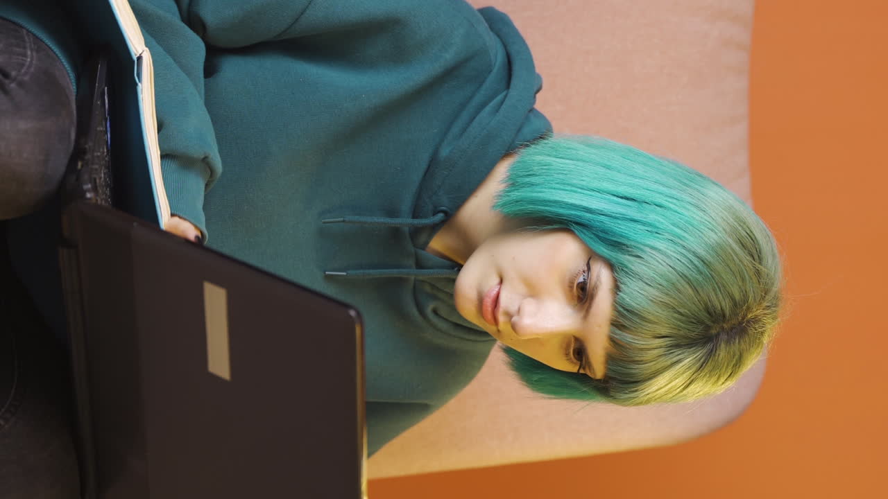 video vertical de una mujer joven concentrada trabajando en una computadora portátil.