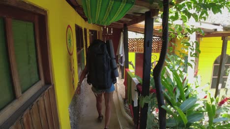 slo mo: woman with large backpack walks down colorful hostel passage