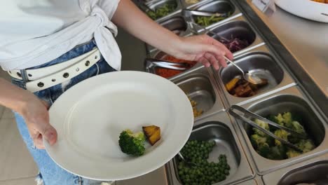 woman at a salad bar selecting vegetables