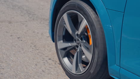 close-up view on the side part of a car and a wheel at moving the road. wheel of luxury car turning slowly on asphalt road.