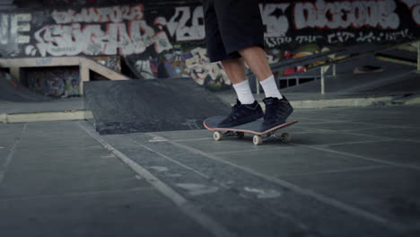 Sportlicher-Mann-Macht-Übungen-Auf-Dem-Skateboard-Im-Skatepark-Mit-Graffitiwand.