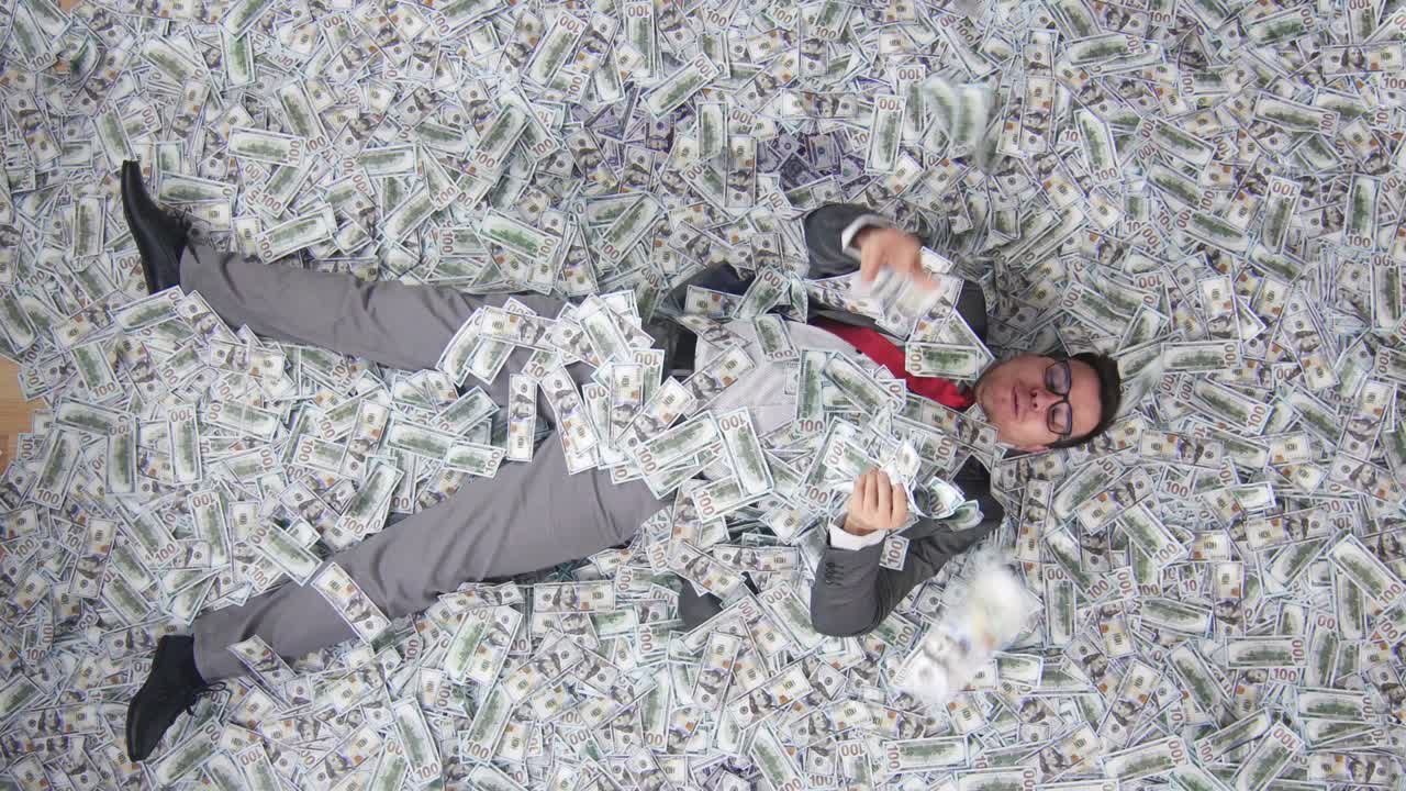 은행 지폐의 배경에 누워있는 기쁜 사업가 위쪽 보기