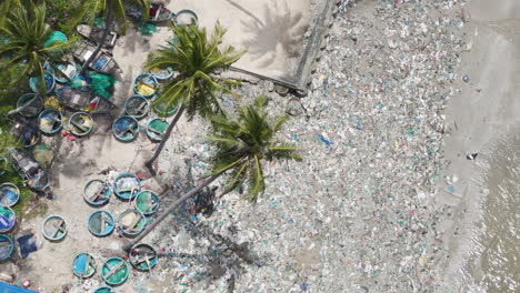 Overhead-view-of-strewn-rubbish-and-plastic-waste-amongst-the-palm-trees-on-a-beach-near-Ham-Tien,-Phan-Thiet,-Vietnam