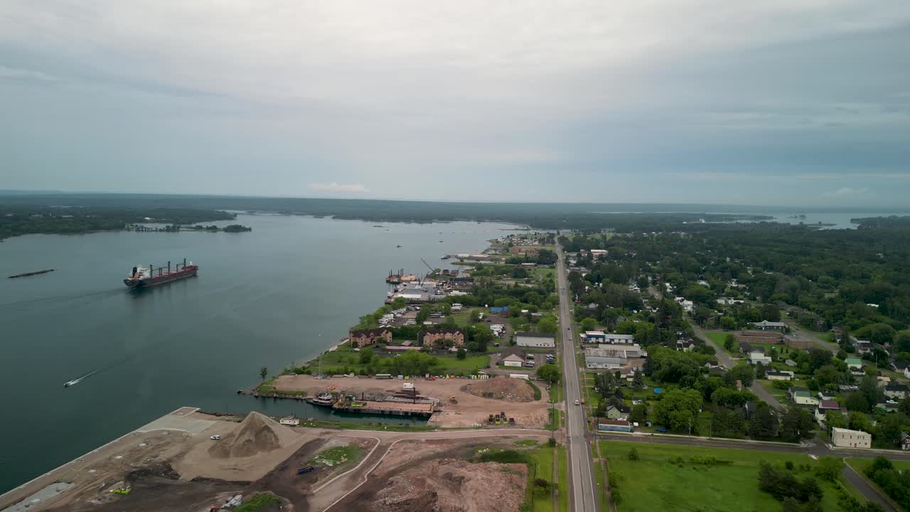 Aerial View of a Cargo Ship on a River by a Waterfront Town and Industrial Port