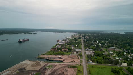 aerial view of a cargo ship on a river by a waterfront town and industrial port