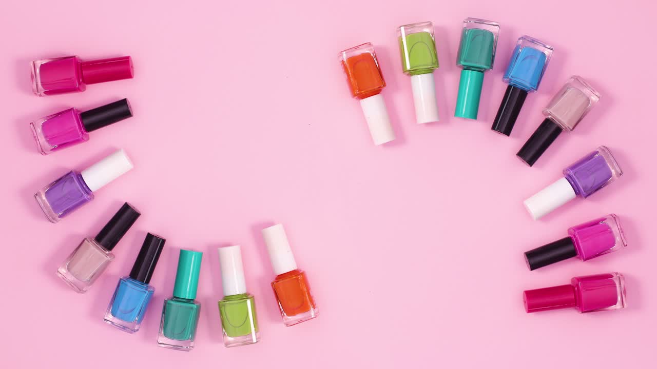 el concepto creativo de manicura de las botellas de esmalte de uñas se mueve sobre un fondo rosa pastel.