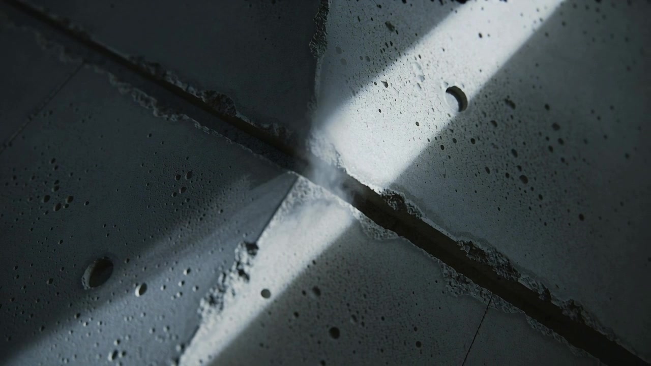 Shifting light beams causing dust plume rising from cross seam concrete joint in building, pits