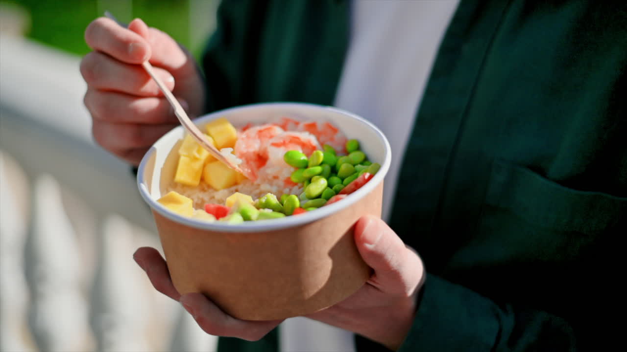 Close view of people placing three poke bowls with vegetables, fruits, fish and seaweed salad on a table