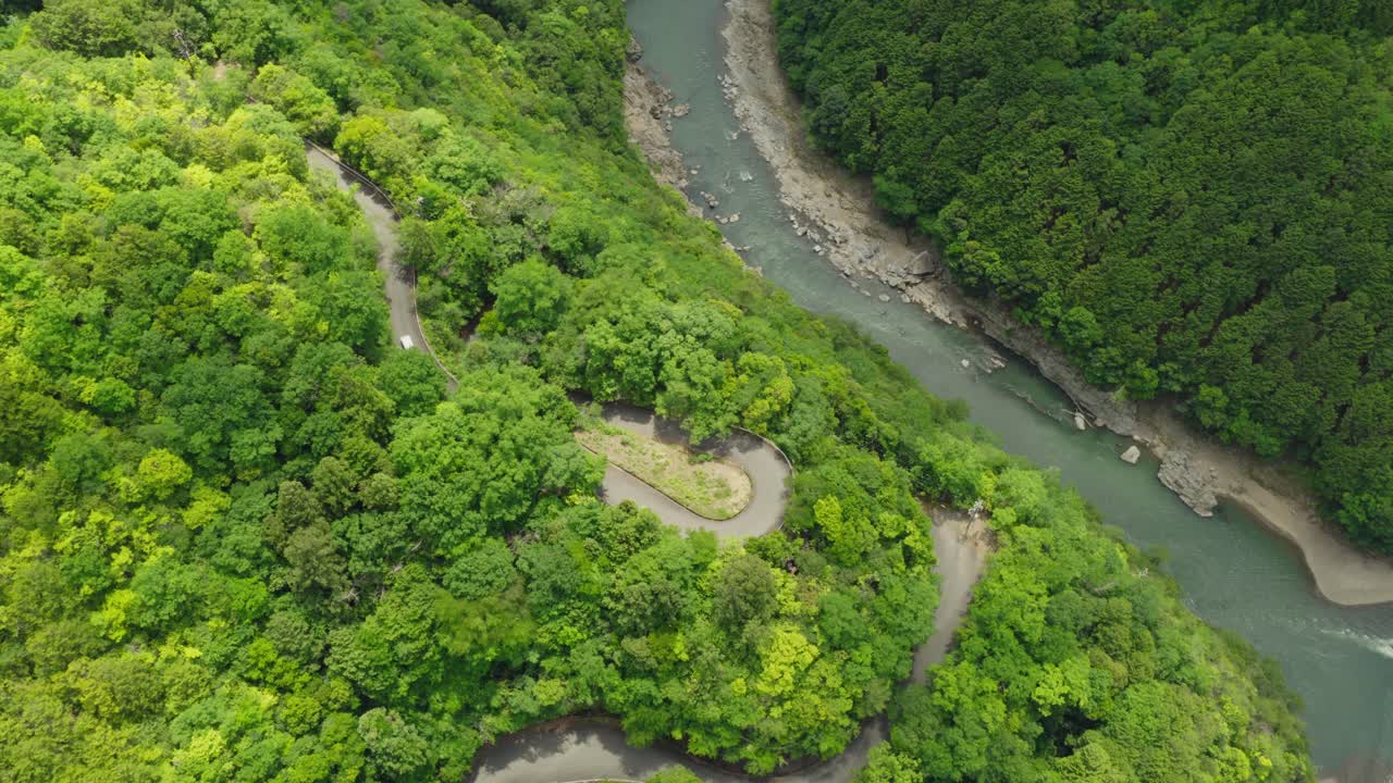 Aerial Top Down White Car Driving on Curvy forested Mountain Road in Kyoto Japan