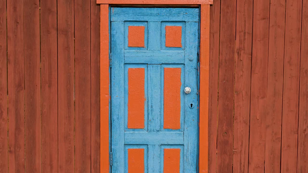 A blue door set in a red wooden wall