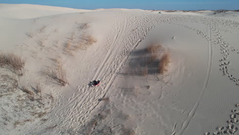 Trineo-En-Colinas-De-Arena-Y-Dunas-En-El-Paisaje-Desértico,-Vista-Aérea-De-Una-Mujer-A-Bordo-De-Trineo-Cuesta-Abajo-En-El-Parque-Estatal-De-Monahans-Sandhills,-Texas,-Ee.uu.