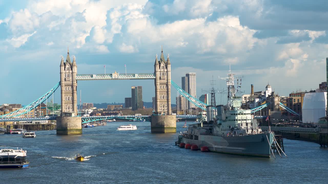 Tower Bridge i London over Themsen med både på vandet og et krigsskib fortøjet i nærheden. Dagstids byudsigt, der viser brostruktur, flodtrafik og byens skyline