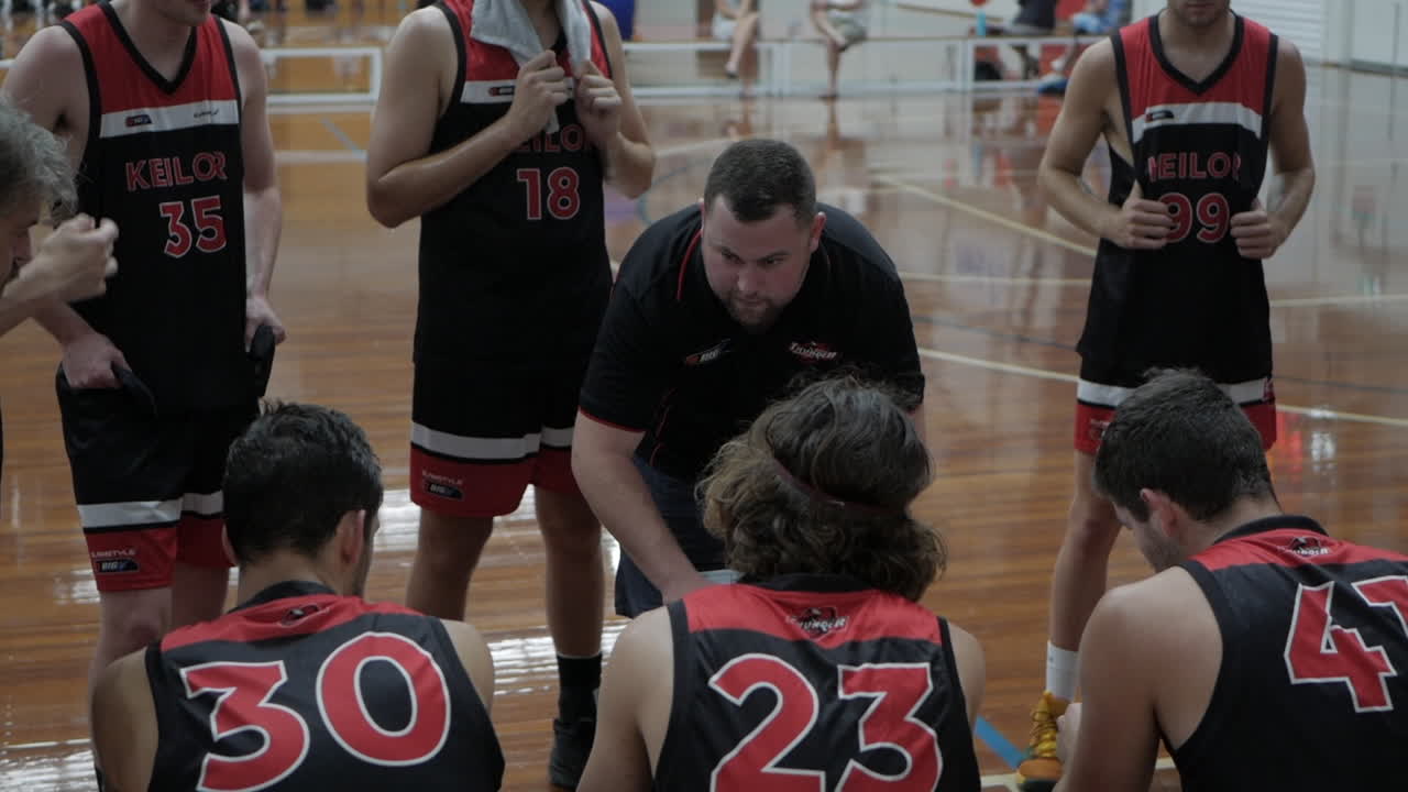 Coach instructing his team during a time out. The coach using his whiteboard to discuss strategies.
