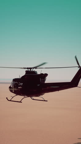 black helicopter flying over a desert