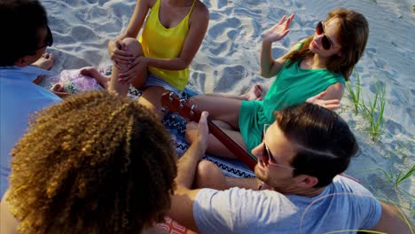 multi ethnic friends with guitar enjoying beach party