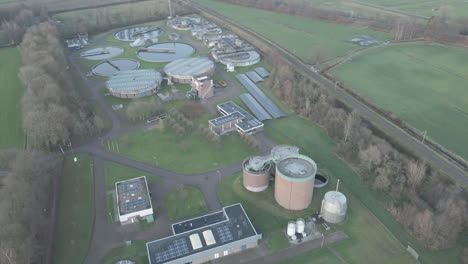 aerial of small sewage water treatment plant in a rural area surrounded by green meadows