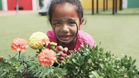 en la escuela, una joven afroamericana examina las flores con una lupa