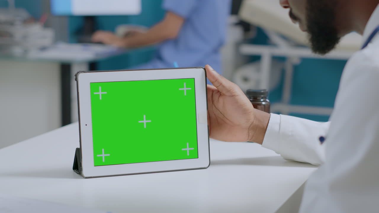 Medical professional using tablet with green screen