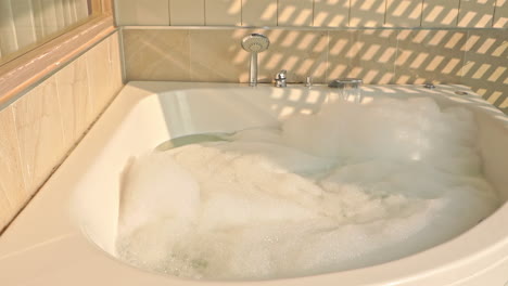 static shot of large spa bubble bath, tap running in golden light