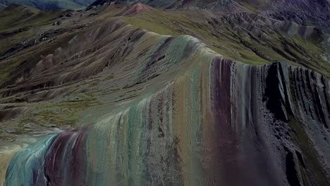 Aerial,-tilt-up,-drone-shot-above-the-Palcoyo-rainbow-mountain,-in-Valle-Rojo,-or-Red-Valley,-Andes-mountains,-partly-sunny-day,-in-Peru,-South-America