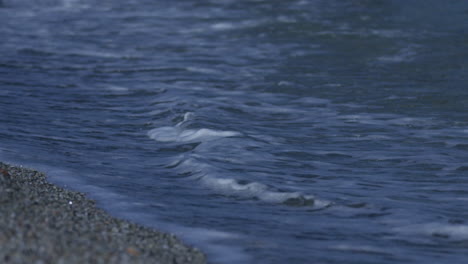 small waves roll in to the shore on the shore line of a pebble beach in marbella, spain