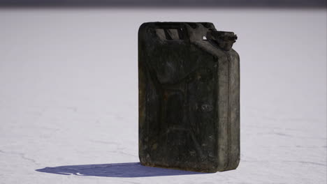 empty fuel canister rests on dry salt flat under bright sunlight