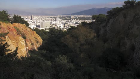View of the city of Athens through a green gully full of trees on Lycabettus hill