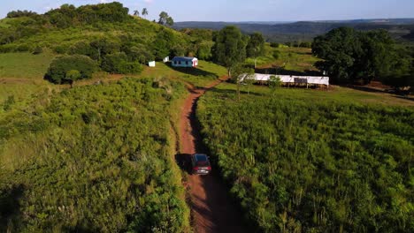 drone shot following a grey vw touareg driving on a dirt path in misiones, argentina during golden hour