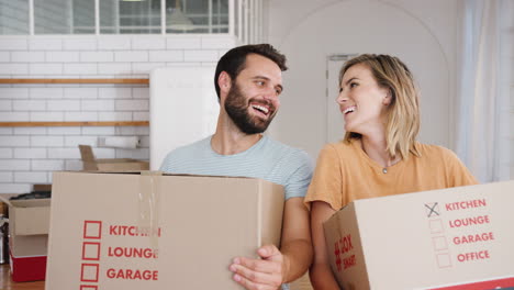 portrait of smiling young couple carrying boxes into new home on moving day