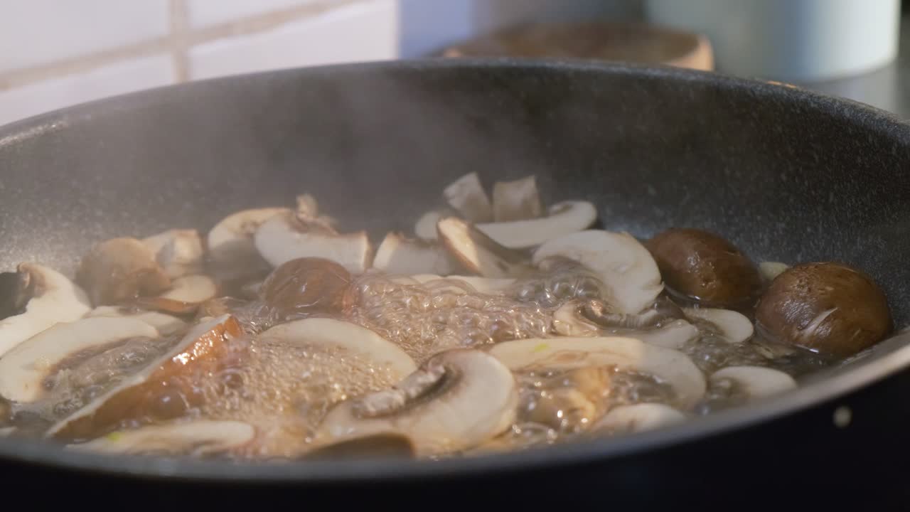 Primo piano di funghi freschi affettati in cottura in una padella per una deliziosa ricetta salutare.