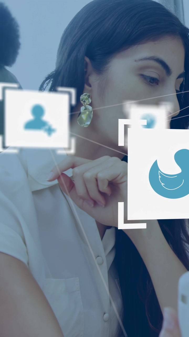 Vertical video: Woman swiping phone at work checking marketing data as social icons moving over her