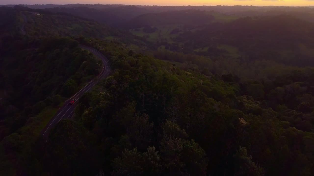 reveladora toma aérea suave de una carretera a través del valle del bosque tropical en kondalilla, australia durante la puesta de sol