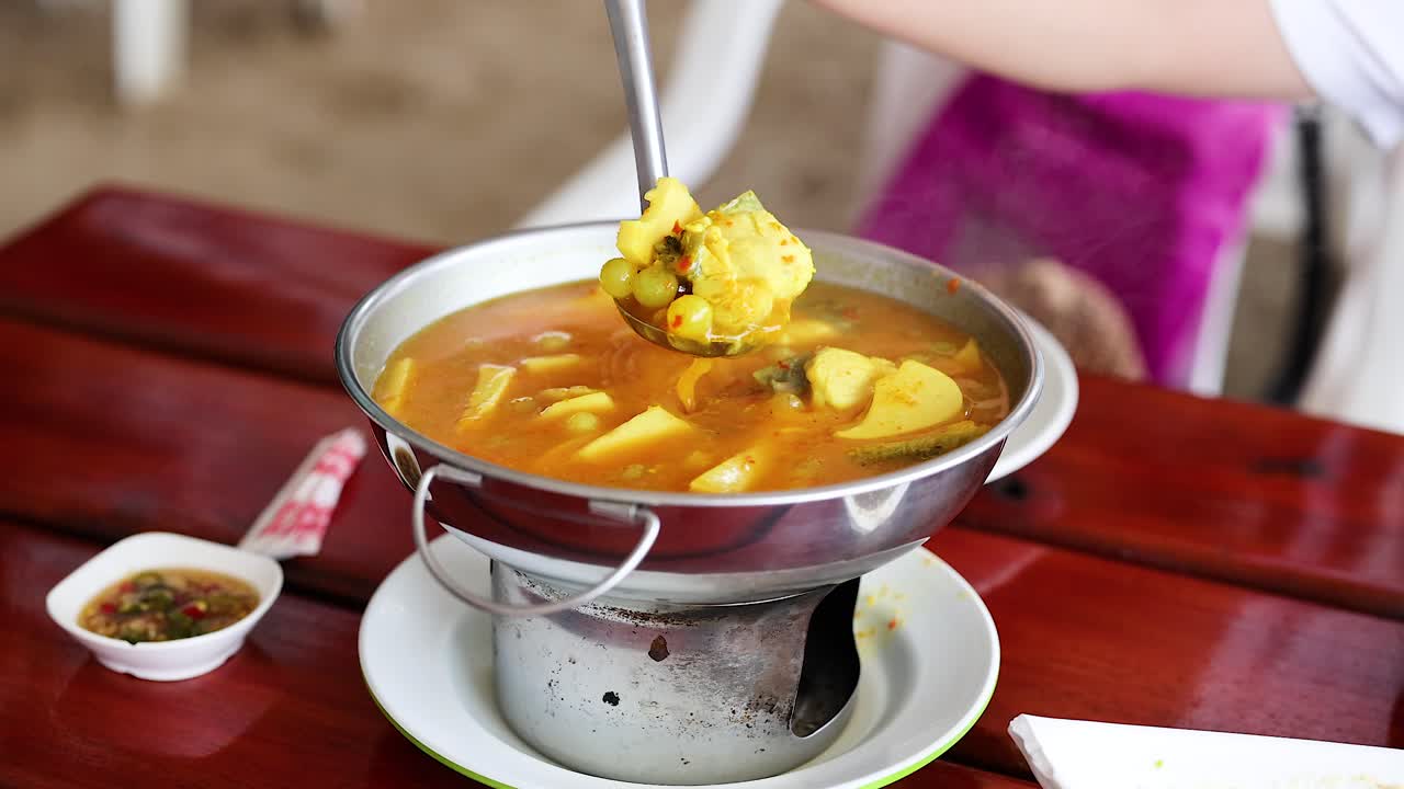 una persona sirve curry amarillo con pescado