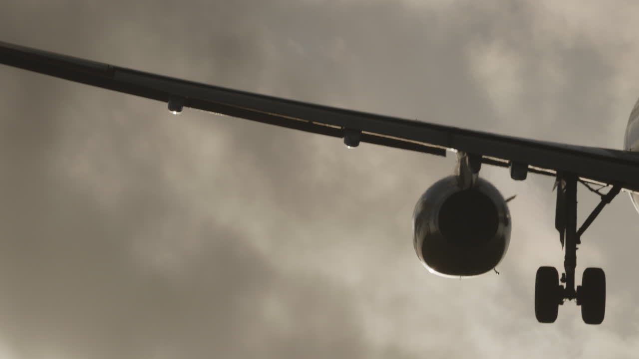 공항에 착륙하기 위해 석양 아래에서 매우 느린 속도로 머리 위를 날아가는 비행기