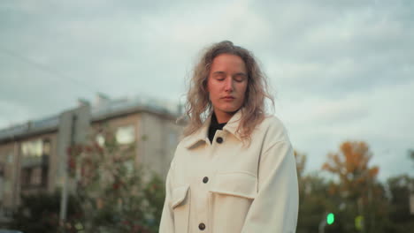 girl glancing up in calm contemplative moment outdoors with blurred view of urban cityscape soft evening sky in background evoking thoughtfulness emotion solitude beauty tranquility